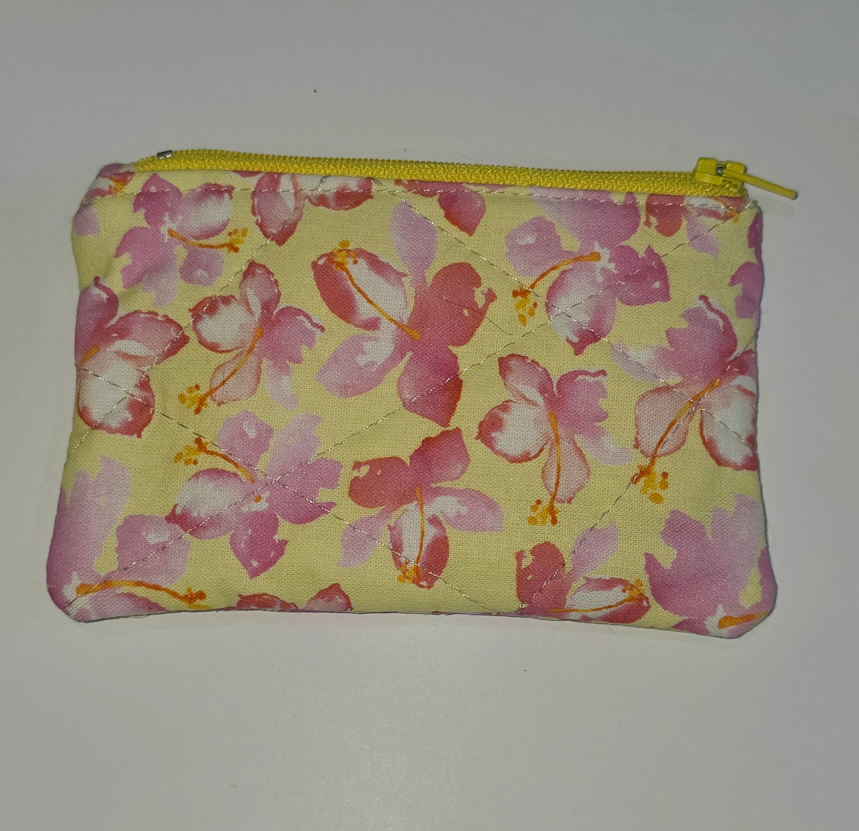 Floral-patterned pouch with a yellow zipper on a white background