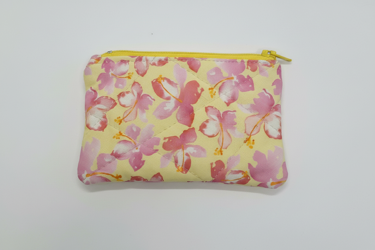 Quilted keychain wallet with floral fabric and yellow zipper on clean white background